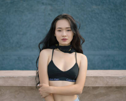 A woman in black top standing next to wall.