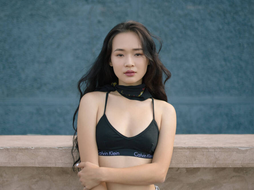 A woman in black top standing next to wall.