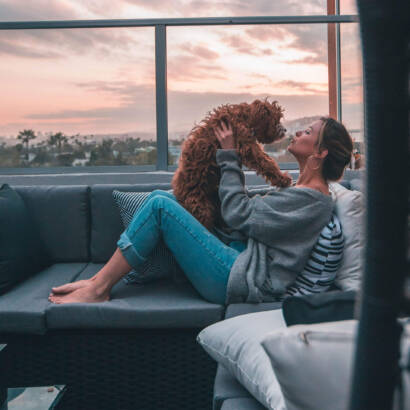 A woman sitting on the couch with her dog.