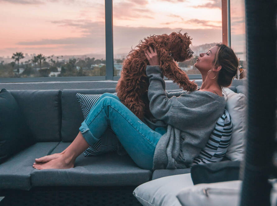 A woman sitting on the couch with her dog.