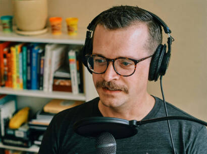 A man with glasses and headphones is recording.