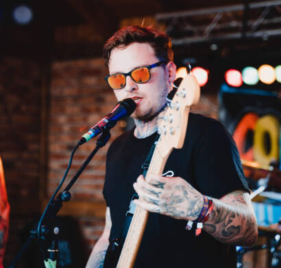 A man with sunglasses on holding a guitar