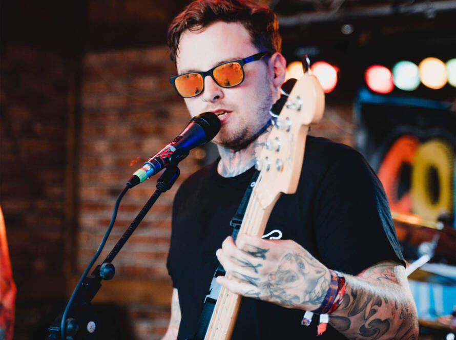 A man with sunglasses on holding a guitar