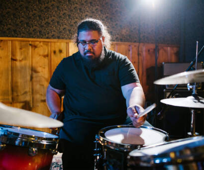 A man is playing drums in the dark