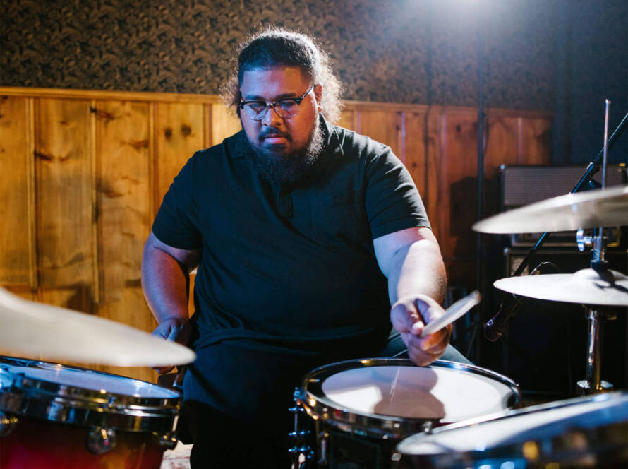 A man is playing drums in the dark