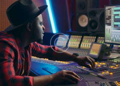 A man sitting at a mixing desk in front of a laptop.