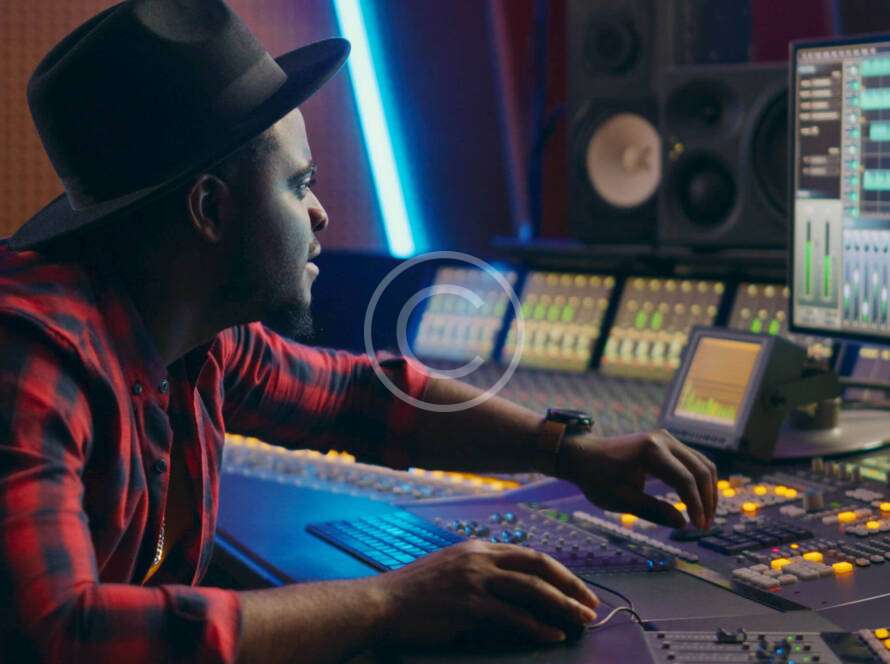 A man sitting at a mixing desk in front of a laptop.