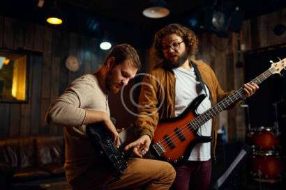 Two men are playing a guitar in the dark.