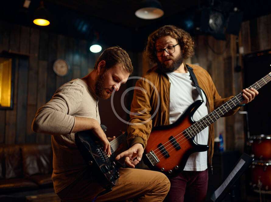 Two men are playing a guitar in the dark.