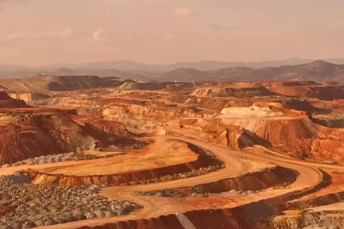 Open-pit mine landscape under cloudy sky.