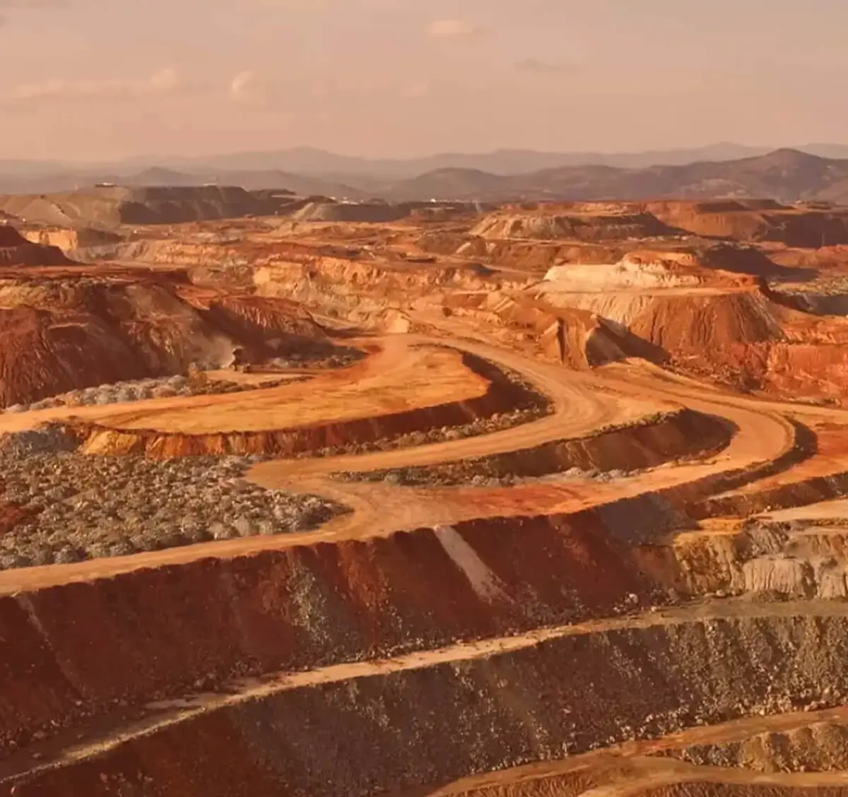 Open-pit mine landscape under cloudy sky.