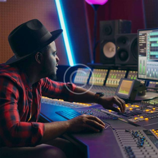 A man sitting at a mixing desk in front of some screens